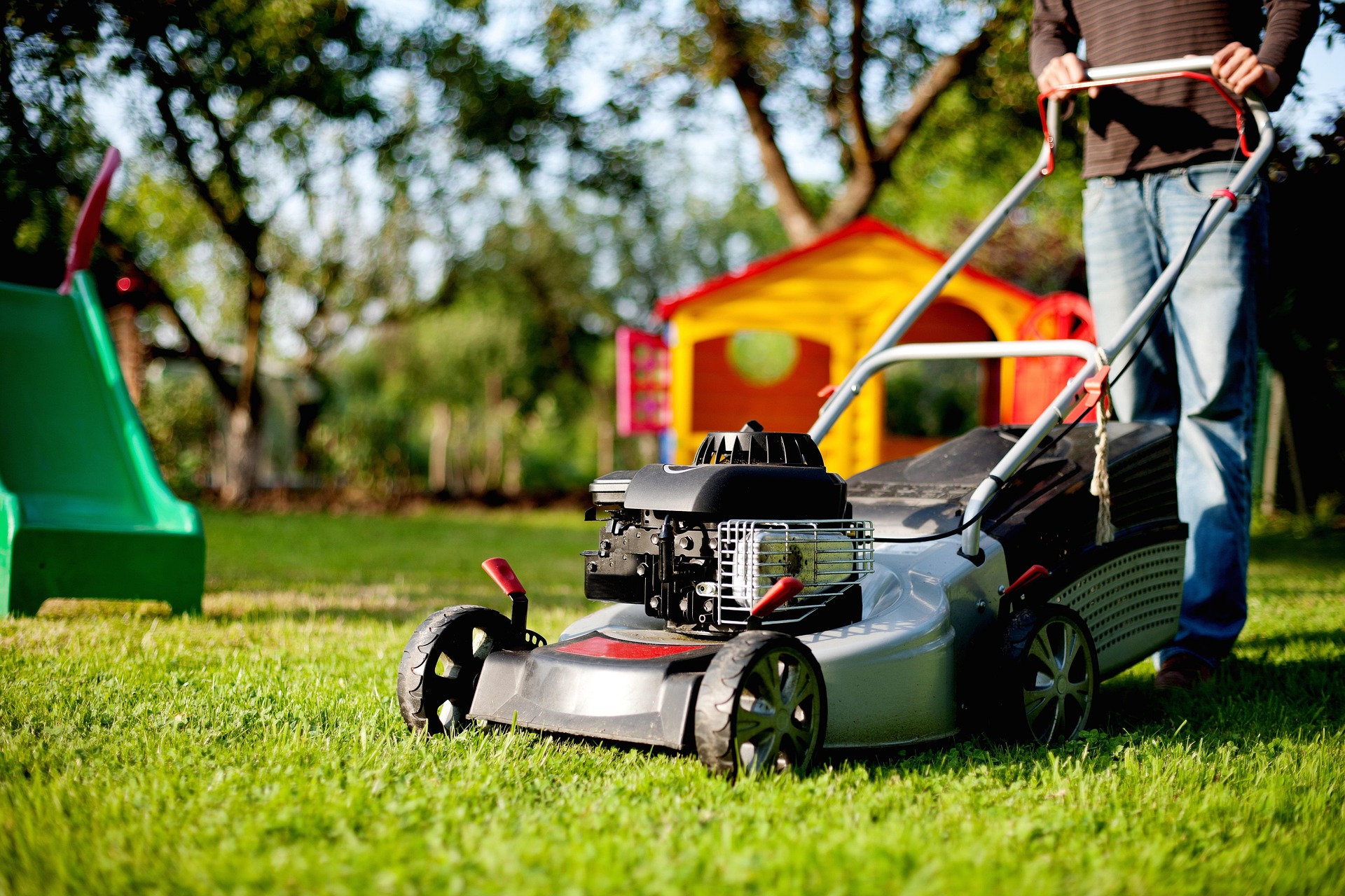 A high school student earning money by mowing a lawn in a suburban neighborhood